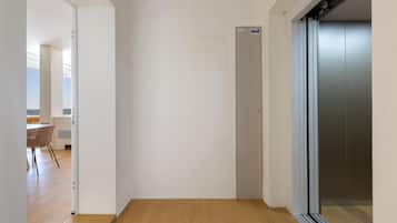A hallway with a wooden floor, a door, and an elevator.