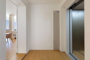 Un pasillo con piso de madera, una puerta y un ascensor.