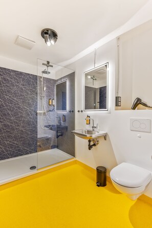 A modern bathroom with a glass-enclosed shower, a sink with a mirror above it, and a toilet. - Studio at Karmelitermarkt | Self-Check-In | Old Town Within Walking Distance (Wien)