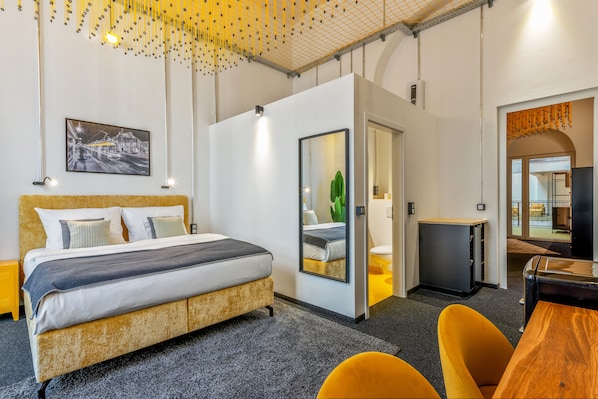 Une chambre d’hôtel moderne avec un grand lit, un bureau et un miroir.