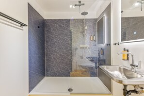Une salle de bain moderne avec une douche à parois de verre, un lavabo et un miroir.