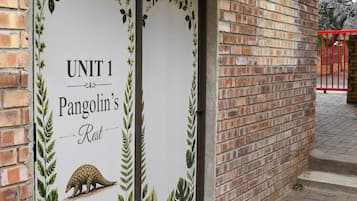 Een bakstenen gebouw met een bord waarop 'UNIT 1 Pangolin's Rest' staat.