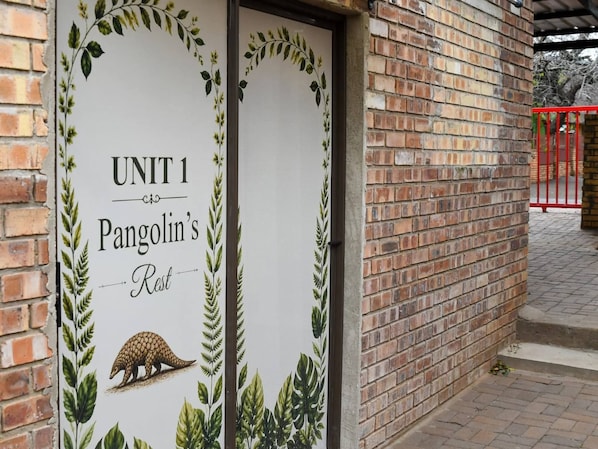 Un edificio de ladrillo con un letrero que dice 'UNIT 1 Pangolin's Rest'.