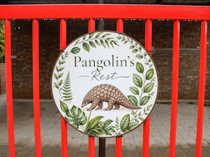 A circular sign with a pangolin illustration and the text 'Pangolin's Rest' against a brick wall background.
