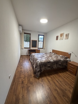 A bedroom with a bed, wooden flooring, a desk, a wardrobe, and a window with curtains. - 10 minutes to the Gondola! Family-sized apartment with 2 bedrooms (Bansko)
