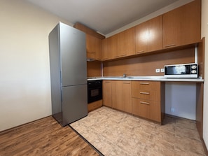 A compact kitchen with wooden cabinets, a stainless steel refrigerator, a microwave, and a dishwasher. - 10 minutes to the Gondola! Family-sized apartment with 2 bedrooms (Bansko)