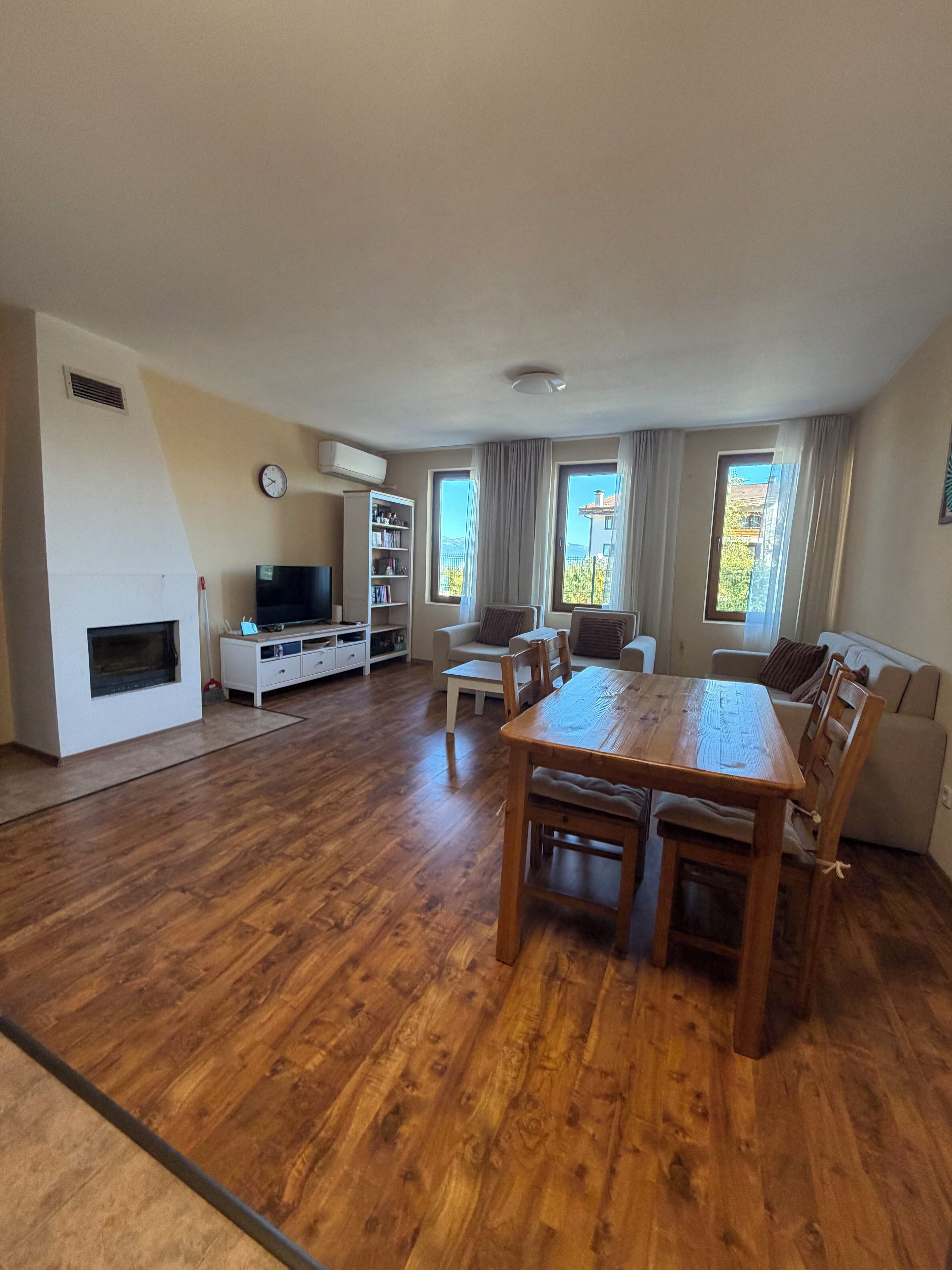 Un amplio espacio de estar con una mesa de comedor de madera, un televisor y una estantería.