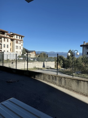 A residential area with a clear view of mountains in the distance, a fenced property, and a street with a concrete barrier. - 10 minutes to the Gondola! Family-sized apartment with 2 bedrooms (Bansko)