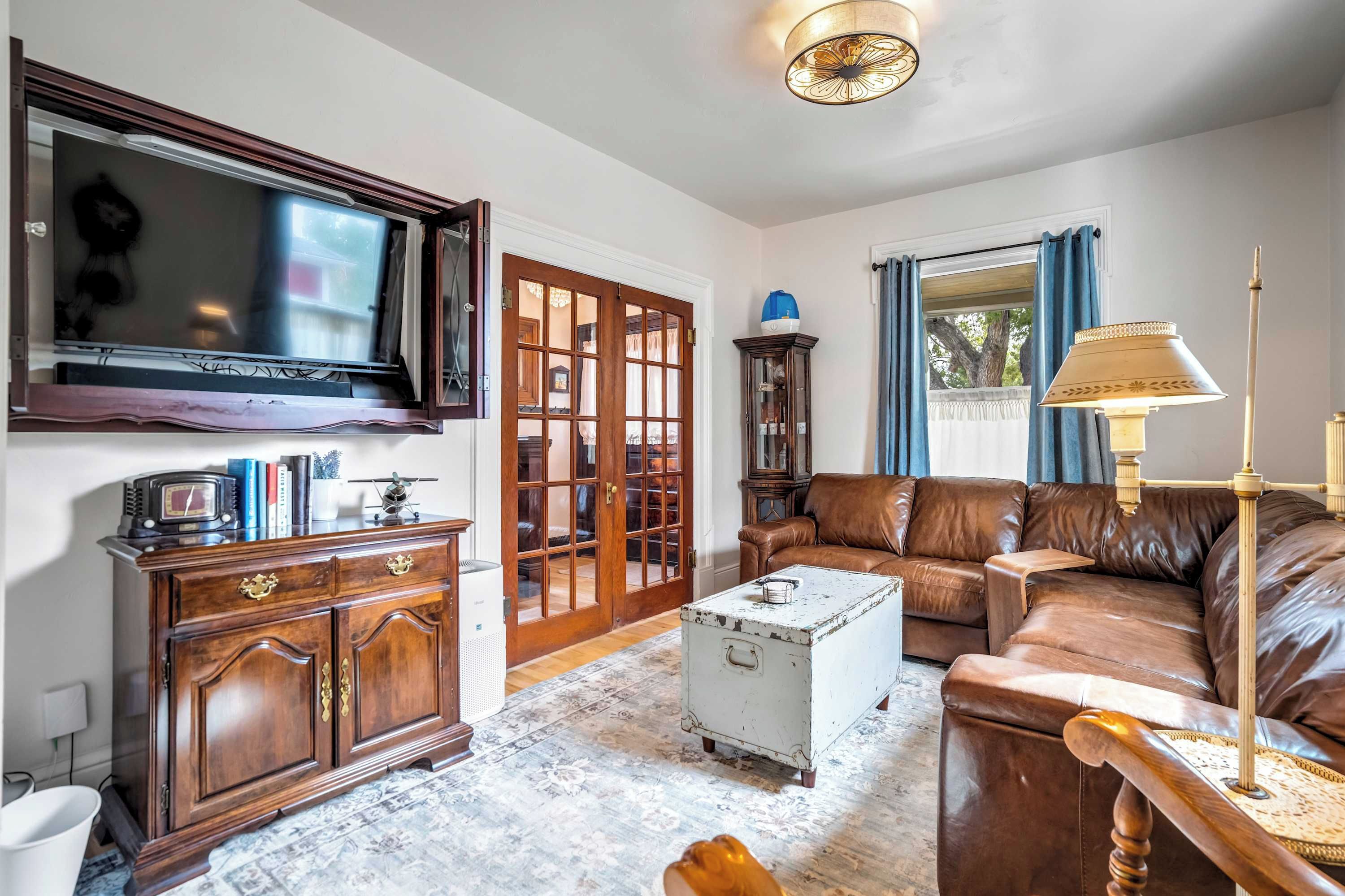 A living room with a television, a wooden cabinet, a leather sofa, a patterned rug, and a decorative lamp.