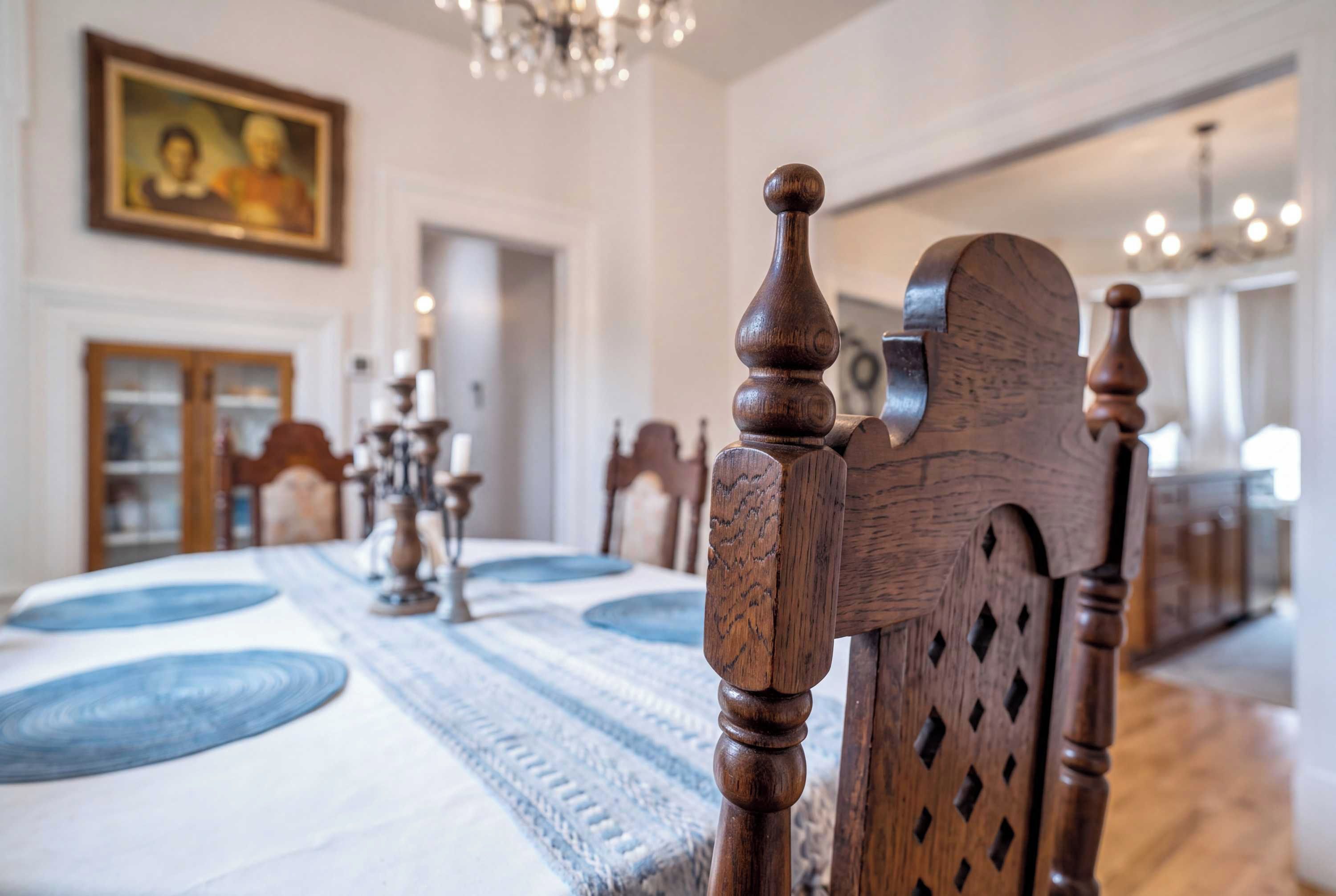 A dining area with a wooden dining table, chairs, and a chandelier.