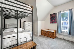 A bunk bed with a wooden headboard, a dresser with drawers, a small wooden chest, and a window with curtains. - Chestnut Hill! Downtown Historic Home w Hot Tub (Colorado Springs)