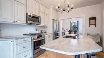 A kitchen with white cabinetry, a central island, stainless steel appliances, and a chandelier.