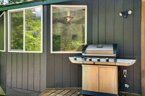 Un barbecue fixé à un mur en bois, avec une fenêtre au-dessus.