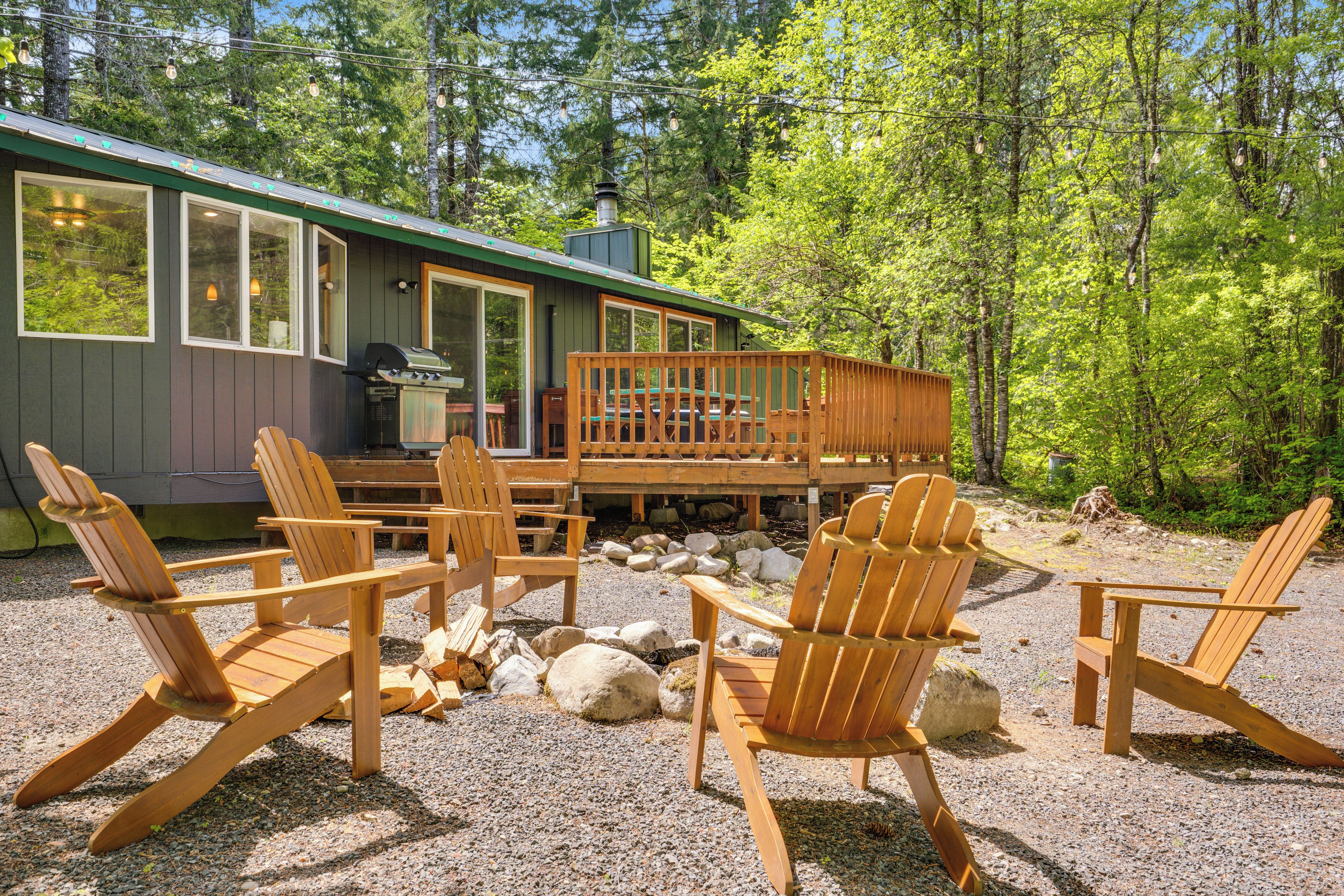 A cabin with a deck, outdoor seating, and a grill.