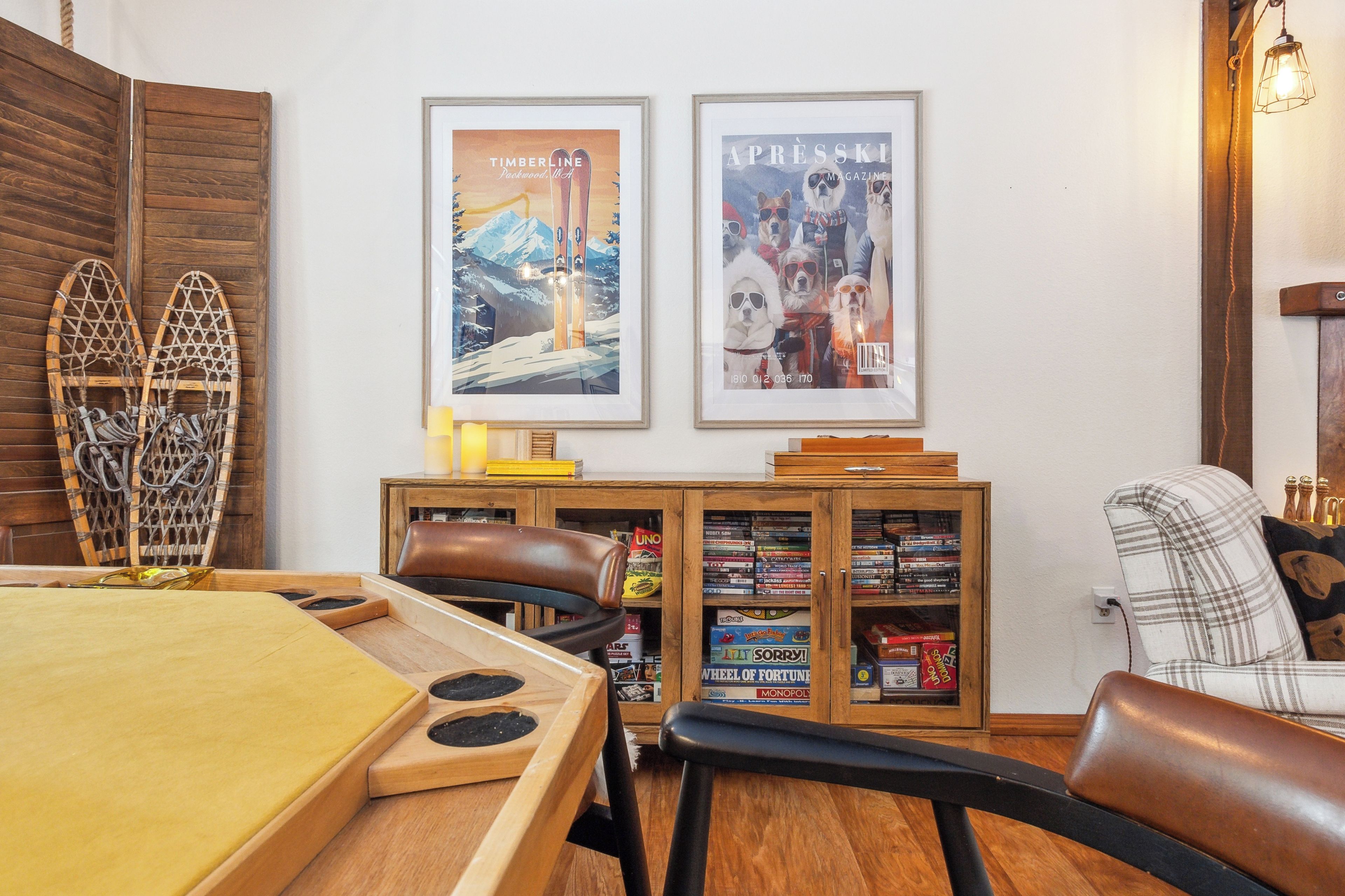 Une pièce chaleureuse avec une table à manger en bois, un fauteuil en cuir et une bibliothèque remplie de jeux de société.