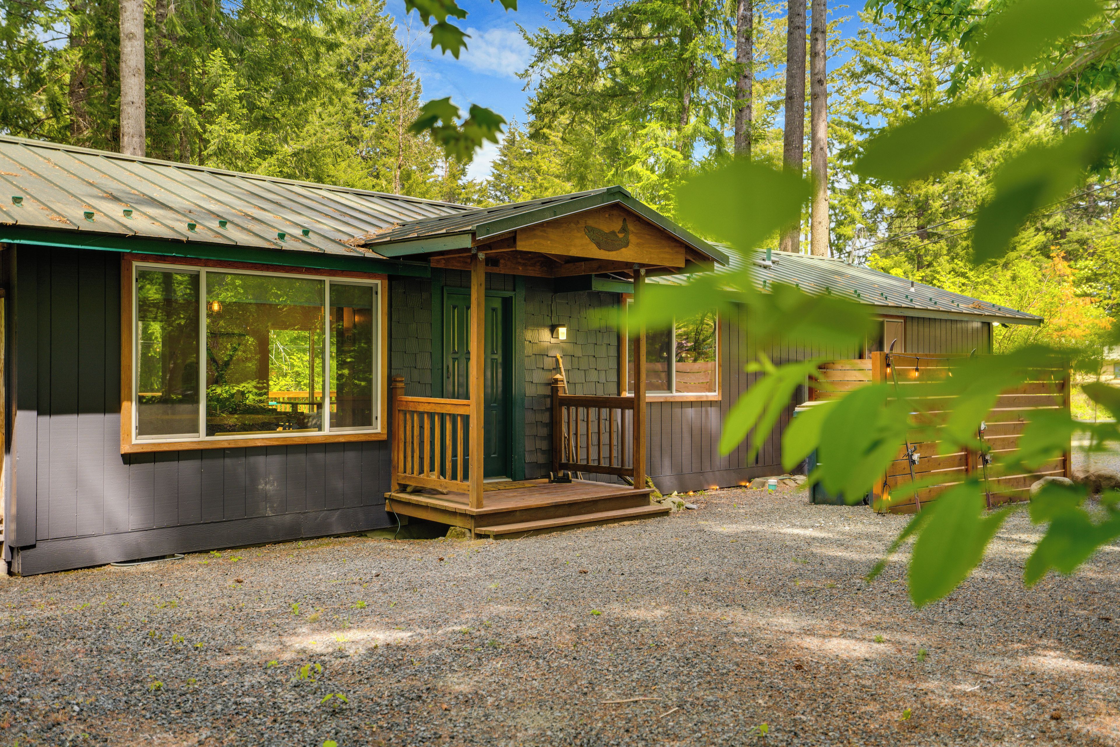 Une cabane dotée d’une véranda, de grandes fenêtres et d’une allée gravillonnée.