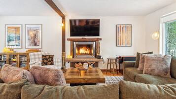 Ein gemütliches Wohnzimmer mit Kamin, Fernseher und einer Couch.