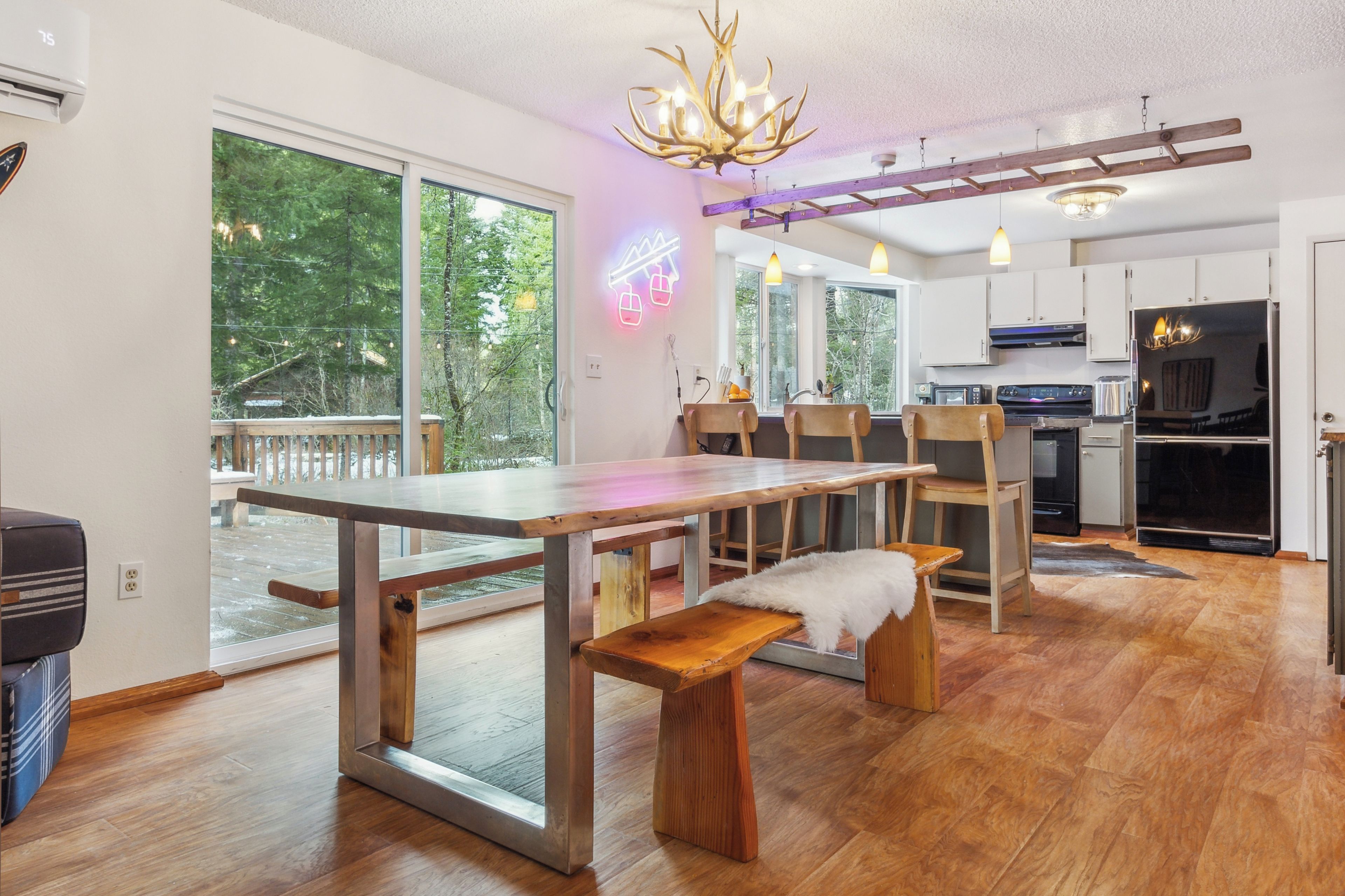 A modern kitchen with a dining area, large windows, and a chandelier.