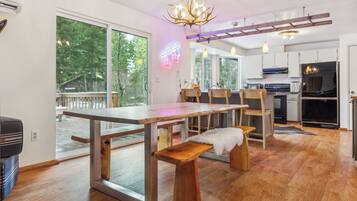 A modern kitchen with a dining area, large windows, and a chandelier.