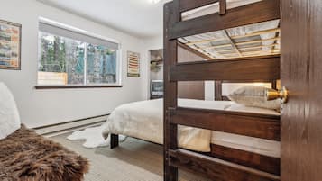 A bedroom with a bunk bed, a window with a view of trees, and a poster on the wall.