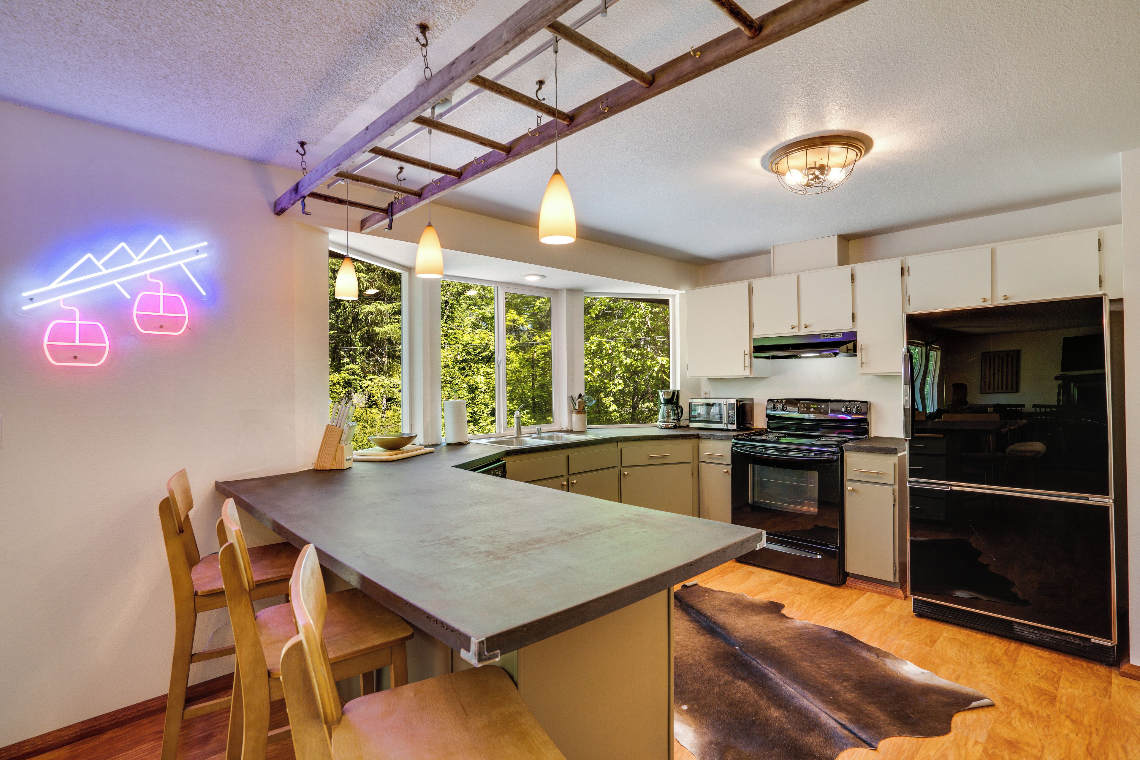 Een moderne keuken met een centraal eiland, houten stoelen, een eettafel en een neonbord.