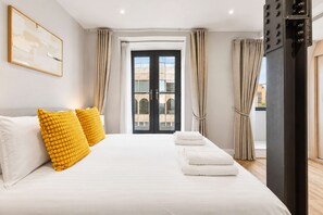 A hotel room with a bed, pillows, a window with curtains, and a view of buildings outside. - City Double VIII - 2BR home with terrace in the City (London)