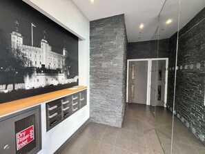 A modern lobby with a stone wall, a reception desk, and a framed historical photo. - City Double VIII - 2BR home with terrace in the City (London)