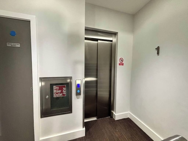 An elevator with a control panel and a sign indicating a dry riser outlet. - City Double IX - Stylish 2BR home in the City (London)
