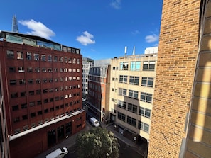 A multi-story building with a red brick facade, large windows, and a parking area with a white car. - City Double IX - Stylish 2BR home in the City (London)