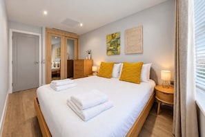 Een hotelkamer met een bed, een kledingkast, een spiegel, een nachtkastje met een lamp en kunst aan de muur.