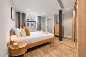 A modern bedroom with a large bed, bedside table, and a wardrobe. - City Double VII - Stylish 2BR home in the City (London)