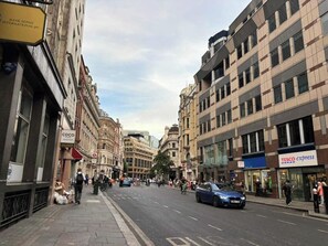 A street with buildings, a blue car, and pedestrians. - City Double VII - Stylish 2BR home in the City (London)