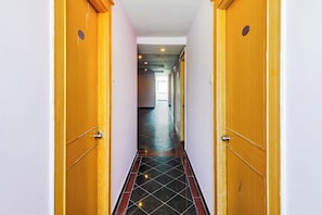 A hallway with wooden doors, each marked with a number. - Hotel O Vaishnavi Palace (Hyderabad)