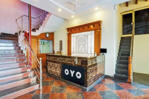 A hotel reception area with a marble staircase, a reception desk, and a clock on the wall. - Hotel O Vaishnavi Palace (Hyderabad)