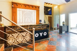En hotellobby med en trappa, en receptionsdisk och ett stort fönster.