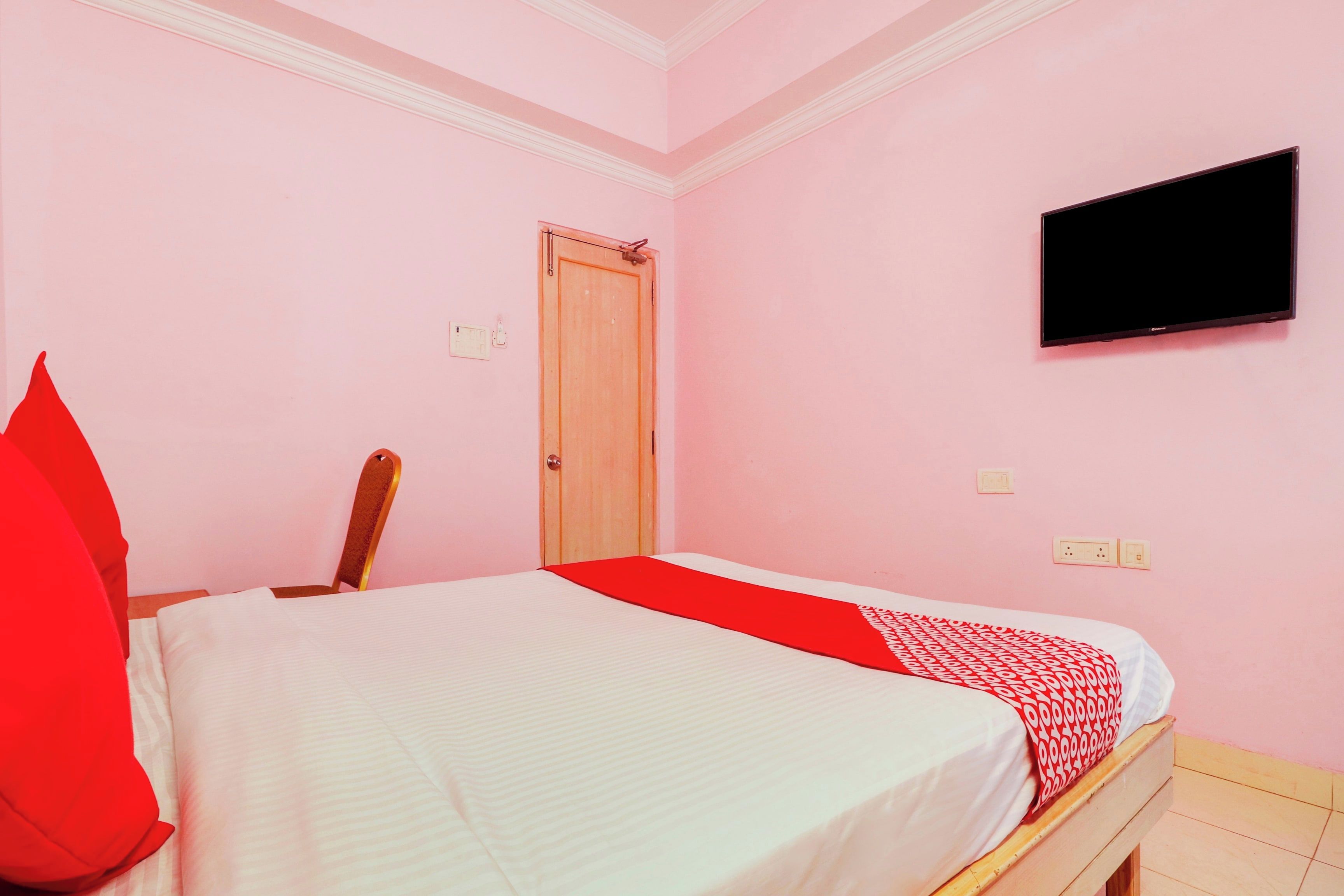 A room with a bed, a television mounted on the wall, and a door.