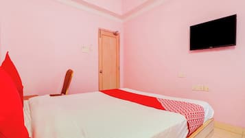 A room with a bed, a television mounted on the wall, and a door.
