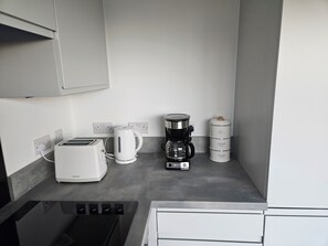 A kitchenette with a toaster, kettle, coffee maker, and a sugar container. -  Beautiful  modern 2 bed flat in Manchester close to Media City/Old Trafford  (Salford)