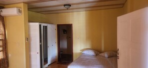 Um quarto pequeno com cama, um guarda-roupa e porta de acesso a um banheiro.