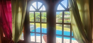 A window with a view of a swimming pool and a lawn. - Castleview villa (Signal Hill)