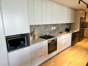 A modern kitchen with white cabinetry, a marble backsplash, a built-in oven, and a stainless steel refrigerator. - Newlands Peak Penthouse (Cape Town)