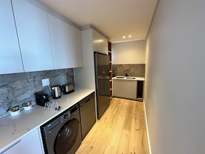 A compact kitchen with a dishwasher, a built-in oven, a sink, and a marble backsplash. - Newlands Peak Penthouse (Cape Town)