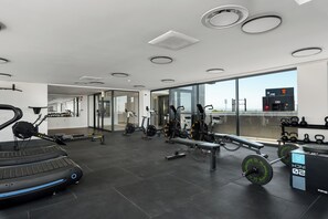 A modern gym with various exercise equipment, a large window offering a view, and a clean, spacious layout. - Newlands Peak Penthouse (Cape Town)