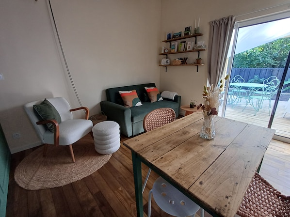 Una sala acogedora con una mesa de comedor de madera, un sofá verde y una silla de mimbre.