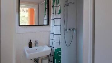 A bathroom with a white sink, a mirror, and a shower.