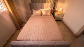 A bedroom with a bed, bedside tables, and a nightstand.