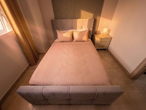 A bedroom with a bed, bedside tables, and a nightstand. - Vrbo Property (Cocoli)