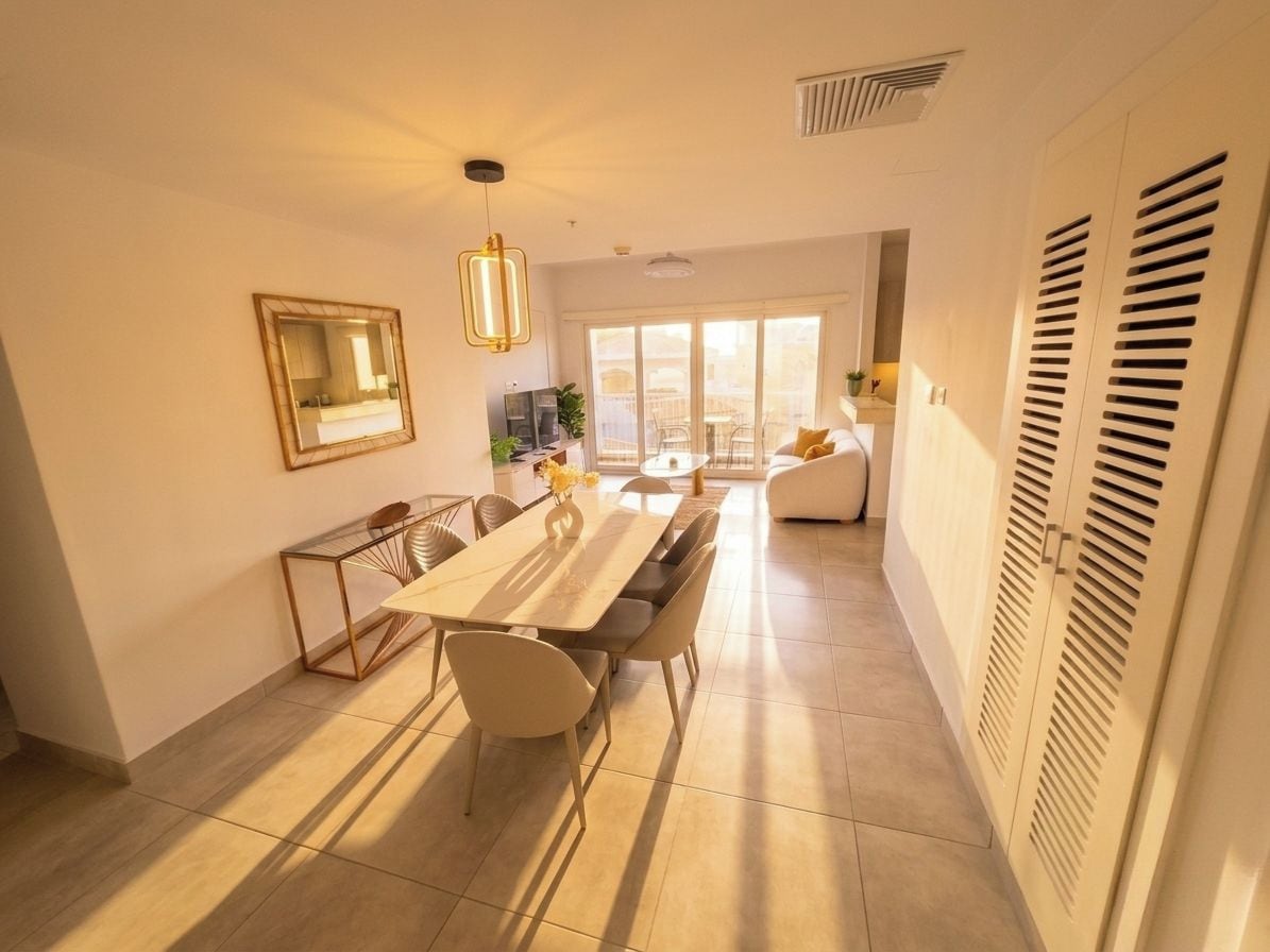 Un comedor moderno con una mesa larga y sillas, una lámpara colgante y vistas a un balcón.
