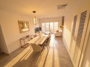 A modern dining area with a long table and chairs, a pendant light, and a view to a balcony. - Private 3-Bedroom Apartment at Golf Resort with Pool 301 (Cocoli)