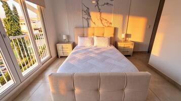 A modern bedroom with a large bed, two bedside tables, and a view of the outdoors.